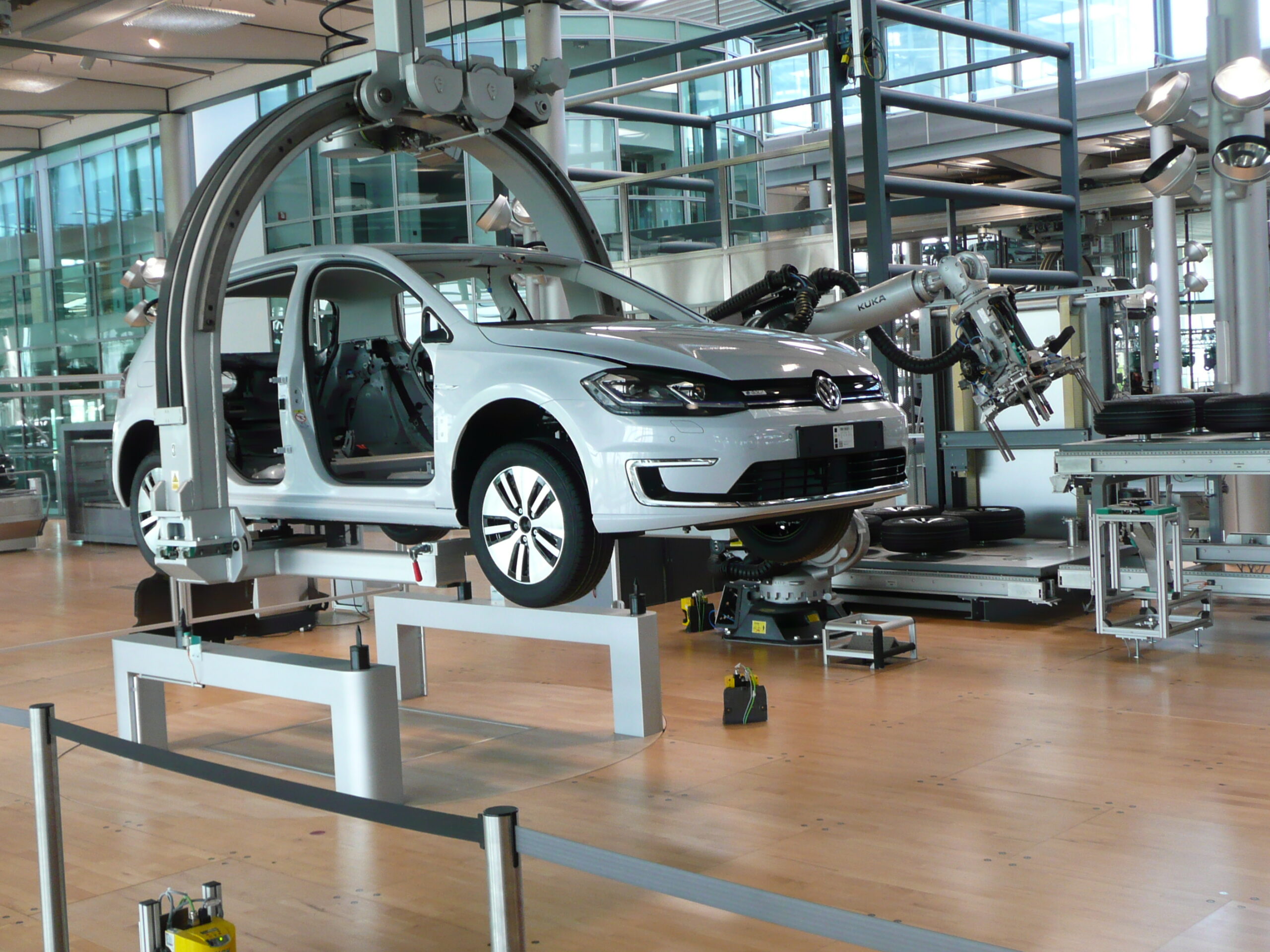 Industrial robotic workstation for installing windows on a Volkswagen e-Golf inside an automotive factory.