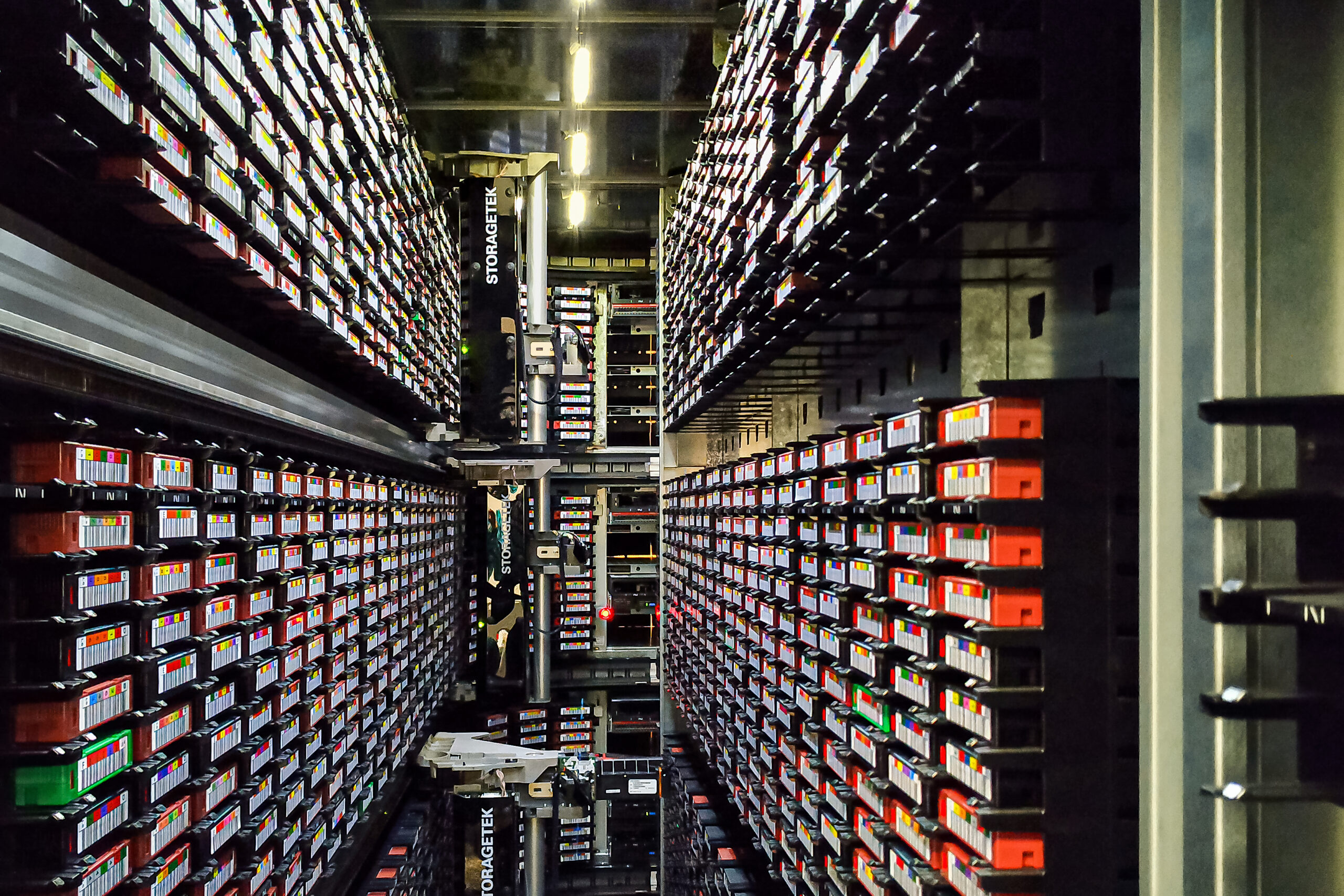 Rows of labeled tape cartridges surrounding robotic mechanisms inside a StorageTek tape library.