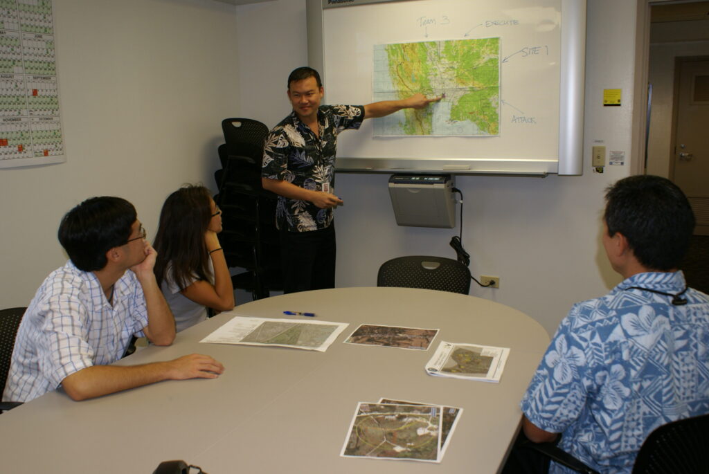 Four NAVFAC planning-team members gathered around a desk while one points to a map.