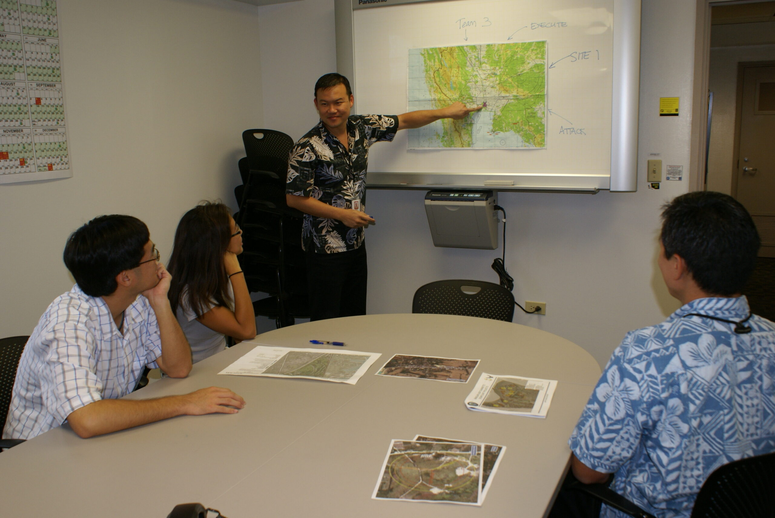 Four NAVFAC planning-team members gathered around a desk while one points to a map.